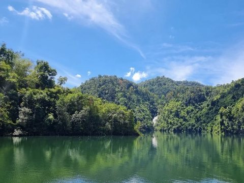 Bờ hồ Tà Đùng phía Quảng Khê, mặt nước phẳng phản chiếu rừng núi và bầu trời trong xanh